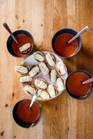 Téléchargez les photos : Une vue verticale sur le dessus de délicieuses bouchées de pain à l'ail au fromage et quatre bols de soupe aux tomates sur la table - en image libre de droit