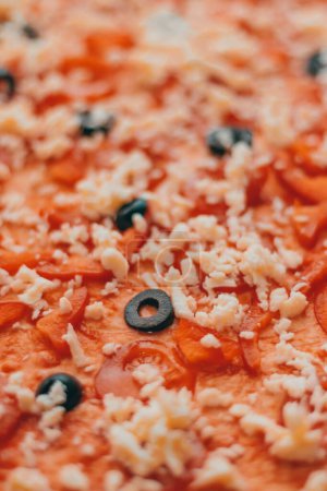 Foto de Un primer plano vertical de una pizza con tomate, queso y aceitunas - Imagen libre de derechos