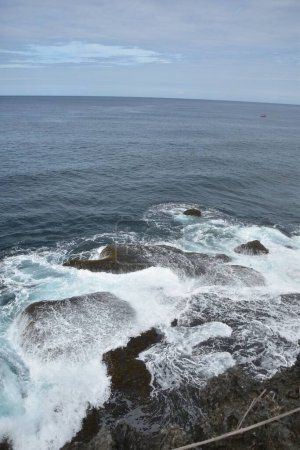 Foto de Un hermoso paisaje de olas aplastando piedras en un día sombrío - Imagen libre de derechos