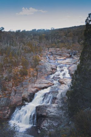 Téléchargez les photos : Peinture d'une cascade traversant les rochers entourés d'arbres pendant l'automne - en image libre de droit
