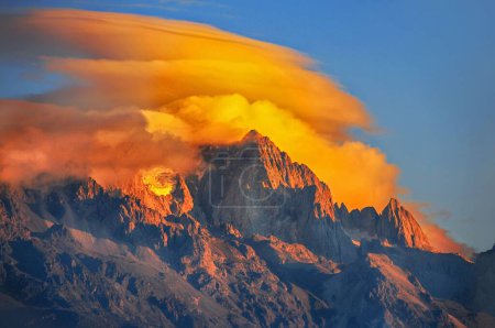 Un pintoresco plano del pico de un monte alto cubierto de nubes ardientes