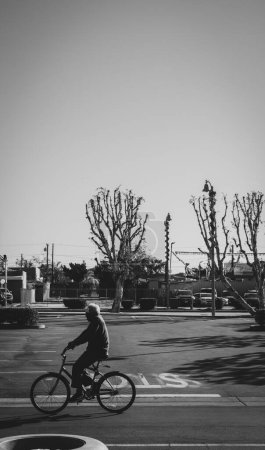 Photo for Old man rides his bike in the parking lot of Bell Plaza in the city of Bell Ca - Royalty Free Image
