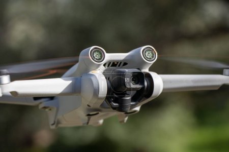 A closeup of the DJI Mini 3 Pro aerial drone against the blurred trees background