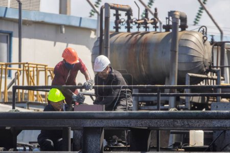 Téléchargez les photos : Trois ingénieurs travaillent à l'installation d'un pipeline - en image libre de droit