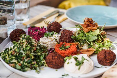 Photo for A closeup of falafel with different salads and dipping sauces on the table in a restaurant - Royalty Free Image