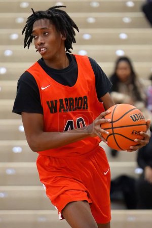 Foto de Un joven jugador de baloncesto negro en camiseta naranja regateando la pelota - Imagen libre de derechos