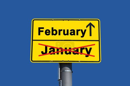Foto de Signo amarillo con letras negras. Por debajo de la palabra Enero tachado en rojo y por encima de ella la palabra Febrero con una flecha. - Imagen libre de derechos