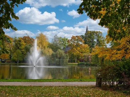 Foto de Un parque con un lago en el que hay una fuente de agua con una iglesia en el fondo en un buen día - Imagen libre de derechos