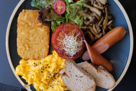 Téléchargez les photos : Une vue imprenable sur un délicieux petit déjeuner avec œufs, champignons, saucisses et légumes - en image libre de droit