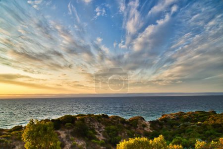 Téléchargez les photos : Une vue sur le paysage marin au lever du soleil avec un ciel nuageux et dramatique en arrière-plan - en image libre de droit