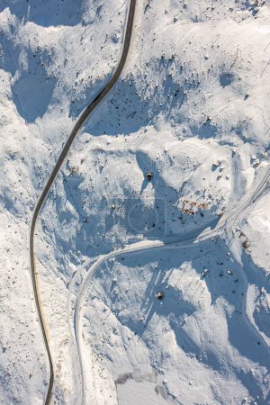 Téléchargez les photos : Vue aérienne verticale d'une route dans le champ blanc enneigé à flanc de colline - en image libre de droit
