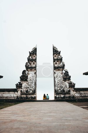 Photo for A vertical shot of a couple sitting near the sea on a sunny day - Royalty Free Image