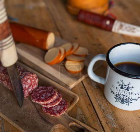 Photo for A closeup of a breakfast on the table with hot coffee, salami and cheese on the blurred background - Royalty Free Image