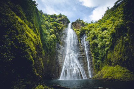 Foto de Un pintoresco disparo de cascadas que fluyen a un lago rodeado de exuberante vegetación - Imagen libre de derechos