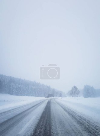 Foto de Una carretera nevada con hielo en los lados y el cielo nublado en el invierno, tiro vertical - Imagen libre de derechos