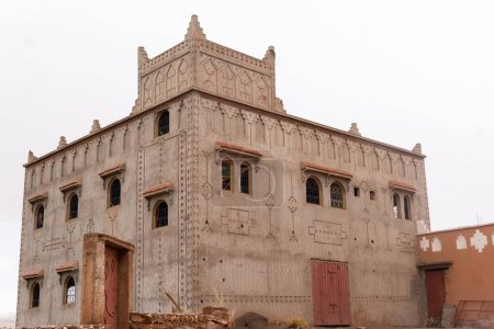 Foto de Un hermoso edificio antiguo con paredes ornamentadas en Marruecos contra el cielo blanco brillante - Imagen libre de derechos