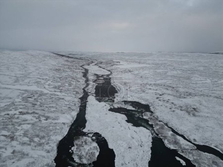 Foto de La vista aérea de un río parcialmente congelado. Paisaje invernal en Islandia. - Imagen libre de derechos