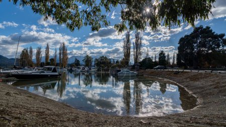 Photo for The reflection of the fluffy clouds and the bright sky on a lake with boats on it - Royalty Free Image