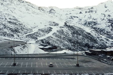 Téléchargez les photos : Un plan aérien de véhicules stationnés à proximité de bâtiments industriels et un flanc de montagne couvert de neige - en image libre de droit