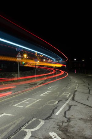 Téléchargez les photos : Un plan vertical d'une route asphaltée vide la nuit avec de longs effets de lumière colorés d'exposition - en image libre de droit