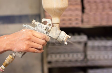 Foto de Una toma de enfoque superficial de manos humanas sosteniendo un pulverizador de pintura en el taller - Imagen libre de derechos