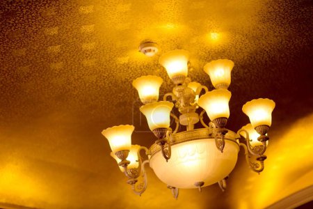Téléchargez les photos : Plan à angle bas d'un lustre vintage de luxe suspendu au plafond, avec de nombreuses ampoules allumées - en image libre de droit