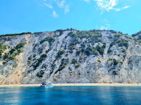 Téléchargez les photos : Un bateau de croisière à la surface d'une mer à côté d'une île rocheuse - en image libre de droit