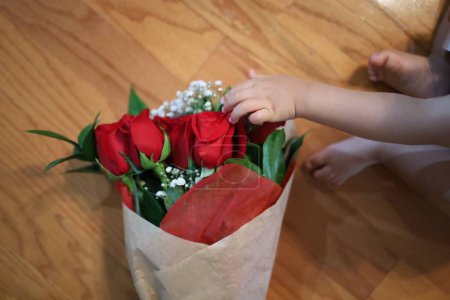 Photo for A closeup of a bouquet of red roses and a kid touching flowers - Royalty Free Image