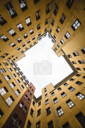 Foto de Un plano vertical de bajo ángulo del cielo visto a través de altos edificios residenciales amarillos - Imagen libre de derechos