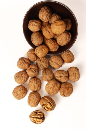 Téléchargez les photos : Walnuts in a brown bowl isolated on a white background - en image libre de droit