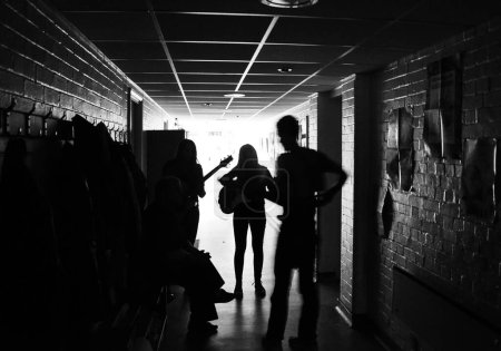 Foto de Una escala de grises de las siluetas de los miembros de la banda que practican en el pasillo de la escuela - Imagen libre de derechos