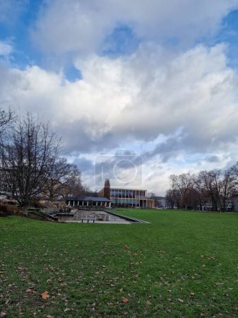 Téléchargez les photos : Un plan vertical de bâtiments au loin et un parc vert sous le ciel bleu et les nuages - en image libre de droit