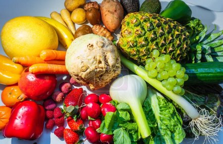 Foto de Una vista superior de frutas y verduras, rábano, fresas, lechuga, uvas y piña con vitaminas - Imagen libre de derechos