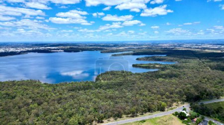 Téléchargez les photos : La vue aérienne des bois verts et du lac reflétant le ciel bleu. - en image libre de droit
