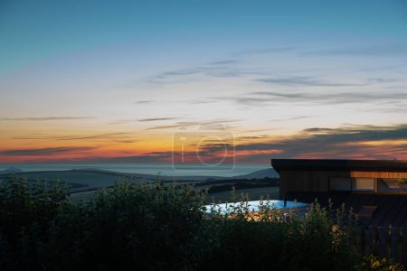 Téléchargez les photos : Un drone de coucher de soleil pittoresque sur une maison côtière et des arbres - en image libre de droit