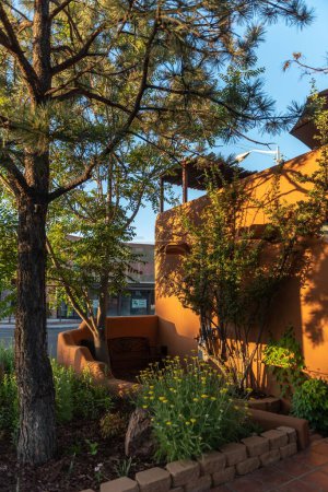 Foto de Un exterior de una casa de arquitectura de estilo Adobe con plantas y árboles, plano vertical - Imagen libre de derechos