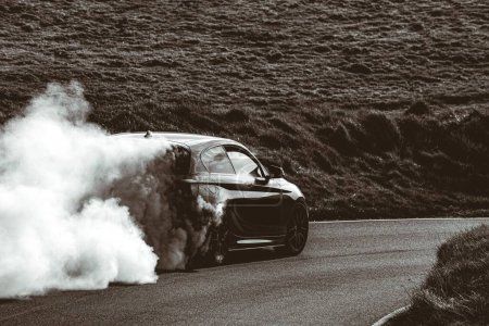 Téléchargez les photos : Une échelle de gris d'une voiture noire qui dérive laissant un nuage de fumée - en image libre de droit