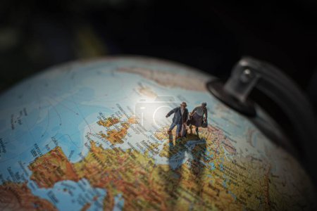 Photo for A closeup of miniature people holding luggage walking on a globe surface - Royalty Free Image