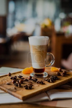 Téléchargez les photos : Gros plan d'un latte stratifié dans un grand verre sur une planche de bois dans un café - en image libre de droit