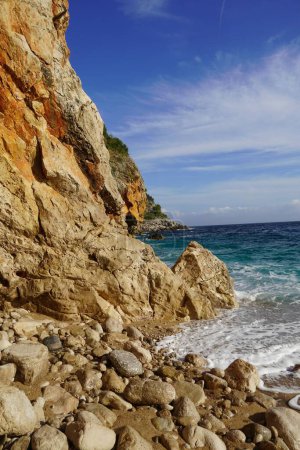 Téléchargez les photos : Vue panoramique d'une plage rocheuse cachée près d'une falaise - en image libre de droit