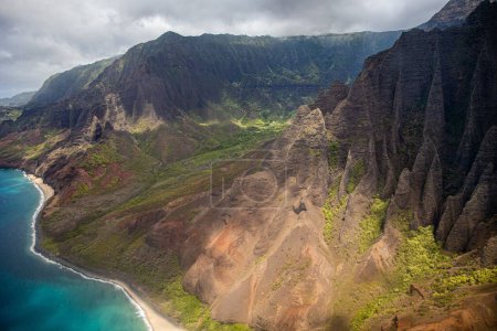 Téléchargez les photos : Un drone de collines sur une côte verte sur une mer sous le ciel nuageux, frais pour l'arrière-plan - en image libre de droit