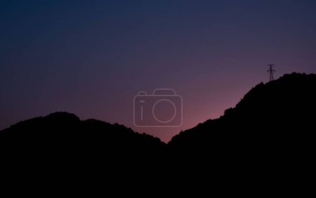 Téléchargez les photos : Une silhouette de collines paisibles au coucher du soleil violet - en image libre de droit