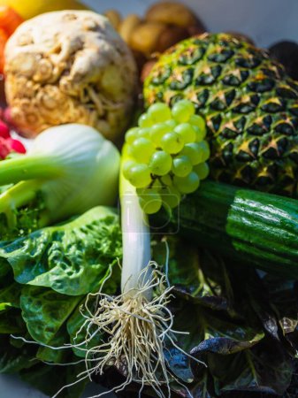 Foto de Una vista superior de frutas y verduras, rábano, fresas, lechuga, uvas y piña con vitaminas - Imagen libre de derechos