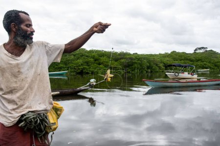 Foto de Pescador sosteniendo línea de pesca con pescado en el gancho. Ciudad de Aratuipe, Bahia, Brasil. - Imagen libre de derechos