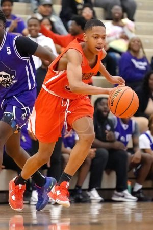 Téléchargez les photos : Un jeune joueur de basket noir en maillot orange dribble la balle - en image libre de droit