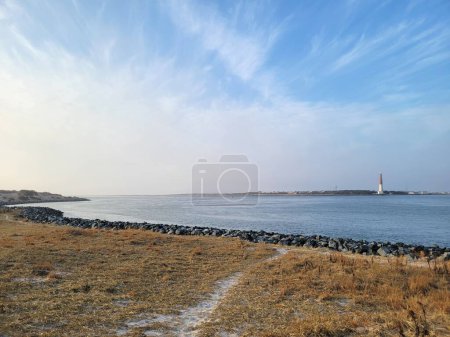 Téléchargez les photos : Une vue paysage sur la mer avec le phare en arrière-plan sur un ciel bleu - en image libre de droit
