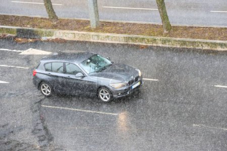 Foto de Vehículo del fabricante BMW circulando por la carretera en el centro de Lisboa con mucha lluvia - Imagen libre de derechos