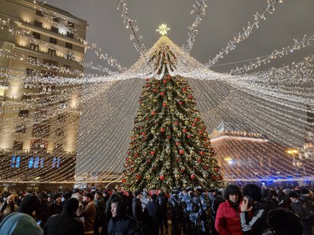Téléchargez les photos : Impressionnantes décorations atmosphériques de Noël et du Nouvel An composées de nombreuses petites lampes autour d'un grand arbre de Noël - en image libre de droit