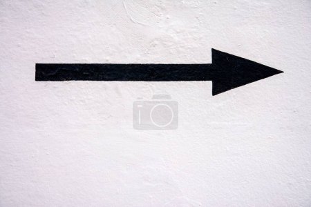 Foto de Flecha pintada negra crujiente sobre fondo pintado blanco brillante texturizado - Imagen libre de derechos