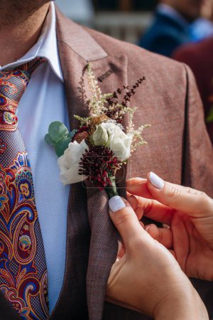 Photo for A female hands adjust the boutonniere on the jacket - Royalty Free Image